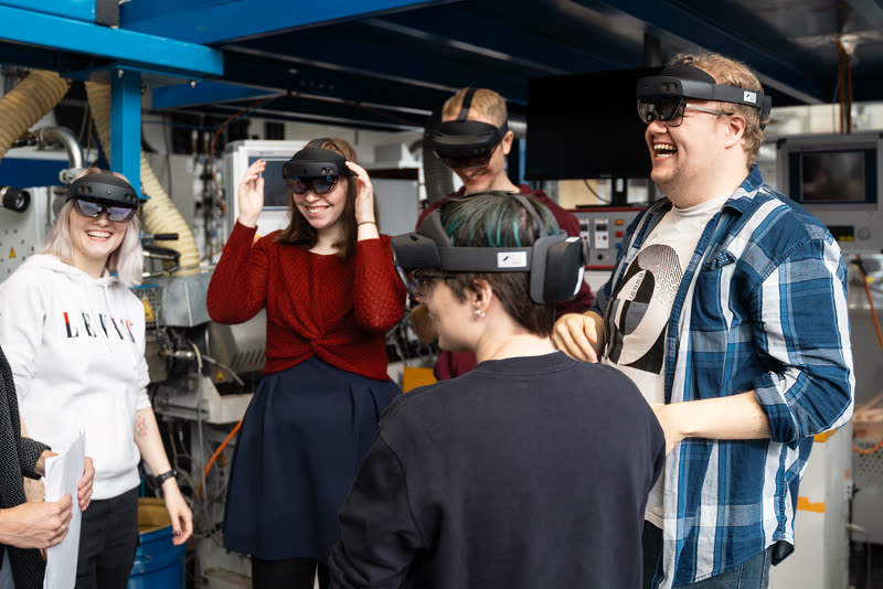 Gruppe mit HoloLens-Brillen lacht gemeinsam in einer Werkstatt