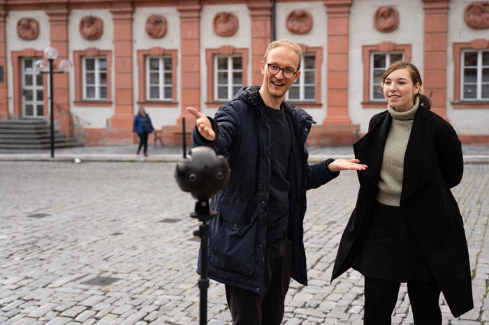 Zwei Personen mit einer 360°-Kamera auf einem historischen Platz